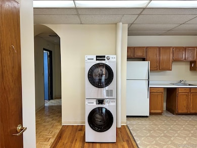 Laundry area featuring arched walkways, stacked washer / dryer, and light wood-style flooring