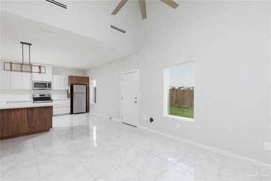 Unfurnished living room with light marble finish flooring, baseboards, a ceiling fan, and a high ceiling