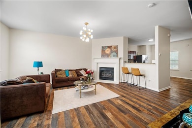 Living area featuring dark wood finished floors, a glass covered fireplace, and a chandelier