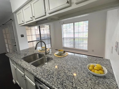 Kitchen featuring white cabinets, light stone coun