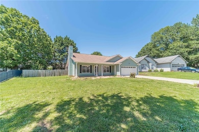 Single story home featuring an attached garage, a chimney, and driveway