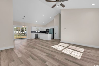 Unfurnished living room featuring high vaulted ceiling, recessed lighting, a chandelier, and light wood finished floors