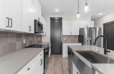 Kitchen featuring stainless steel appliances, white cabinets, sink, light hardwood / wood-style floors, and backsplash