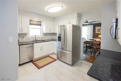 Kitchen with white cabinets, ceiling fan, stainless steel appliances, and backsplash