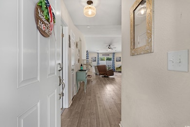 Entrance foyer with wood finished floors, a ceiling fan, and a textured wall