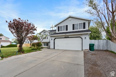 View of front of house with fence, an attached garage, a front lawn, brick siding, and driveway
