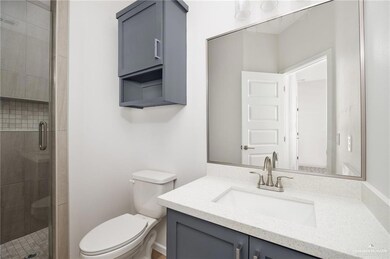 Bathroom featuring a shower stall, toilet, and vanity