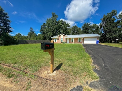View of front of home featuring a garage, asphalt driveway, brick siding, and a metal roof