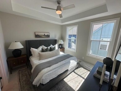 Bedroom featuring a tray ceiling, carpet flooring, and ceiling fan