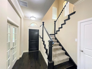 Entryway featuring ornamental molding, dark wood-style flooring, and stairway