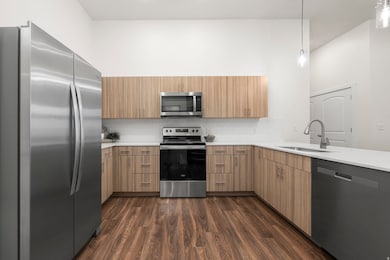 Elevated kitchen with mid-tone cabinets, quartz counters, tile backsplash, and stainless steel appliances. *Refrigerator not included.