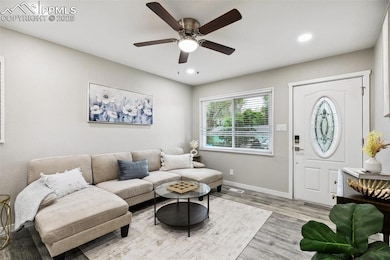 Living room with light wood-style floors, baseboards, ceiling fan, and recessed lighting