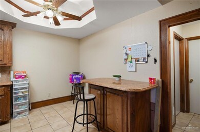 Bar area featuring light tile patterned floors, ceiling fan, and light stone counters