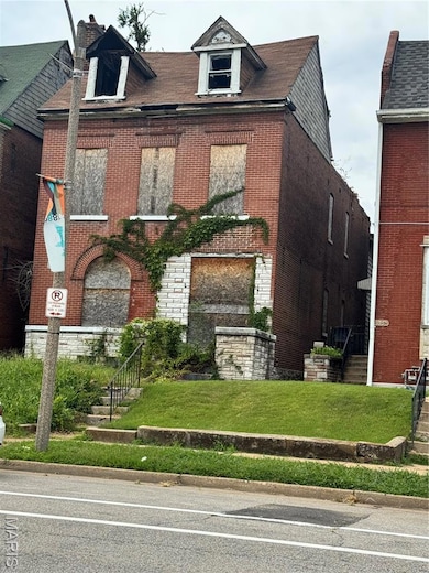 View of front facade featuring brick siding, a front yard, stone siding, and a chimney