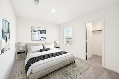 Bedroom with light colored carpet and a spacious closet