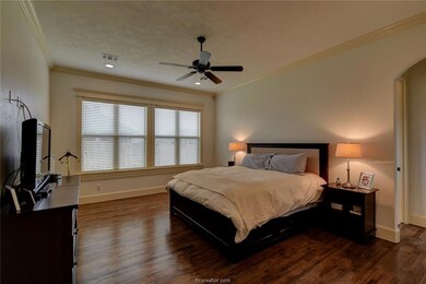 Bedroom with arched walkways, crown molding, dark
