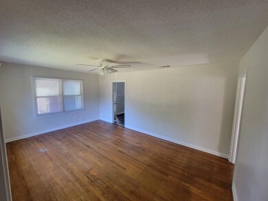 Empty room featuring a textured ceiling, dark wood-type flooring, and ceiling fan