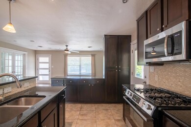 Kitchen featuring decorative backsplash, appliances with stainless steel finishes, dark brown cabinetry, and a textured ceiling