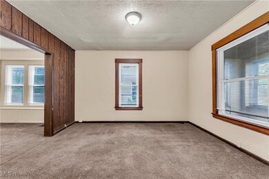 Carpeted empty room with wooden walls and a textured ceiling