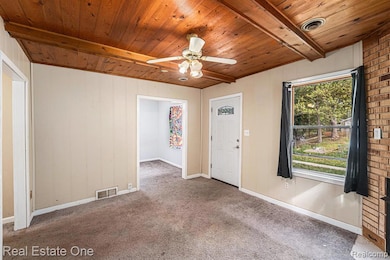 Carpeted entryway featuring a wood ceiling with exposed beams and ceiling fan