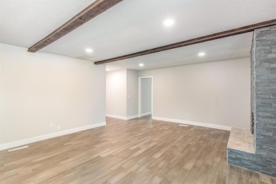 Basement featuring light wood-style flooring, a textured ceiling, and recessed lighting