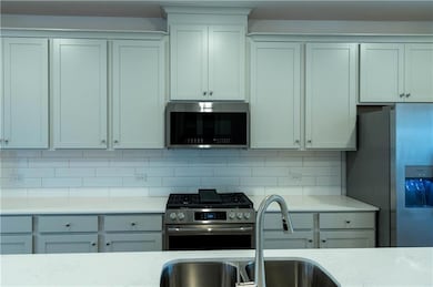 Kitchen featuring appliances with stainless steel finishes, light stone countertops, and decorative backsplash