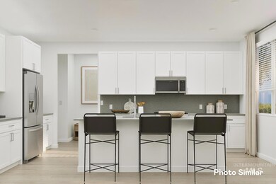Kitchen featuring tasteful backsplash, stainless steel appliances, light wood-style floors, and a kitchen island with sink