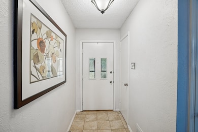 Entryway featuring a textured ceiling, tile patterned floors, and a textured wall