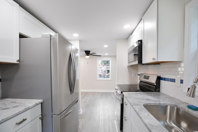 Kitchen with appliances with stainless steel finishes, a ceiling fan, tasteful backsplash, white cabinets, and recessed lighting