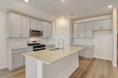 Kitchen featuring light stone counters, sink, an i
