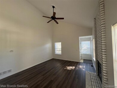 Unfurnished living room featuring high vaulted ceiling, dark wood-style floors, a fireplace, and a ceiling fan