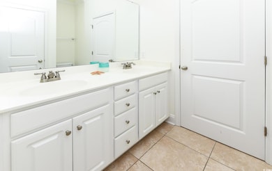 Full bath with double vanity and light tile patterned floors