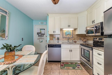 Kitchen featuring light stone counters, a textured ceiling, decorative backsplash, stainless steel appliances, and a sink