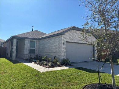 This photo shows a modern, single-story brick home with a two-car garage. It features a well-maintained front yard with a small tree and landscaped garden. The house has a covered entryway and a clean, inviting exterior.