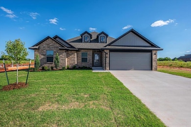 View of front of home with a garage, driveway, a front yard, and brick siding