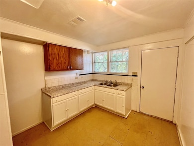Kitchen with light countertops, light flooring, a textured ceiling, and white cabinets