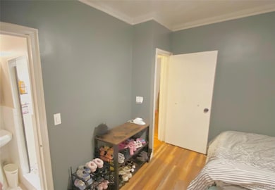 Bedroom featuring wood finished floors and crown molding