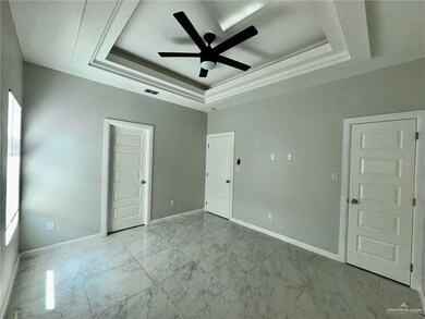 Empty room featuring a raised ceiling, ceiling fan, and light marble finish floors