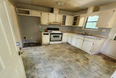 Kitchen with white electric range, a sink, open shelves, light countertops, and under cabinet range hood