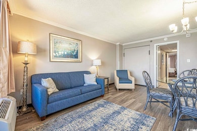 Living area featuring a textured ceiling, ornamental molding, dark wood finished floors, and an inviting chandelier