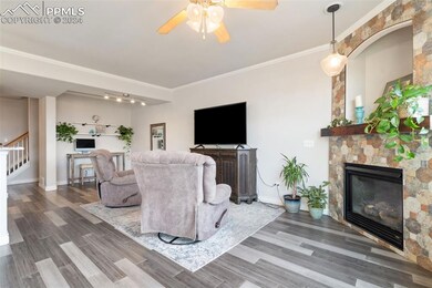 Living room with ceiling fan, a fireplace, crown m