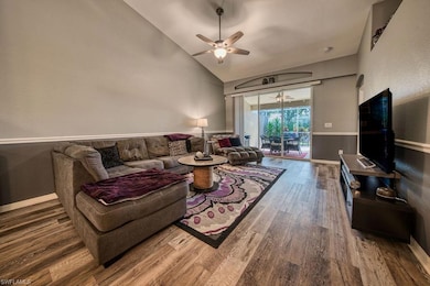 Living area with high vaulted ceiling, wood finished floors, and ceiling fan