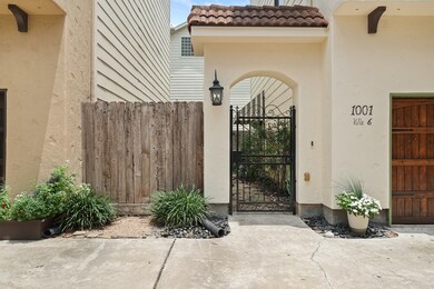 An arched and wrought iron gated entry illuminated