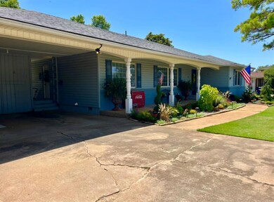 Ranch-style home featuring a shingled roof, driveway, an attached carport, and a porch