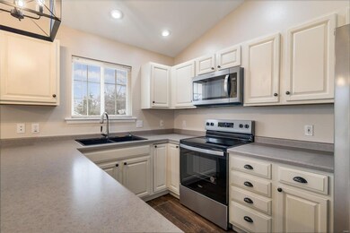 Kitchen featuring white cabinets, sink, vaulted ceiling, medium oak / wood-style flooring, and stainless-appliances