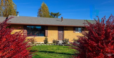 View of front of home with a front yard, brick siding, and a shingled roof