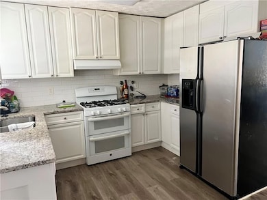 Kitchen with stainless steel fridge, double oven range, a sink, and white cabinetry