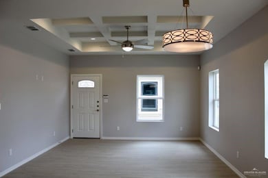 Entrance foyer with coffered ceiling, ceiling fan, light wood-style flooring, and beam ceiling
