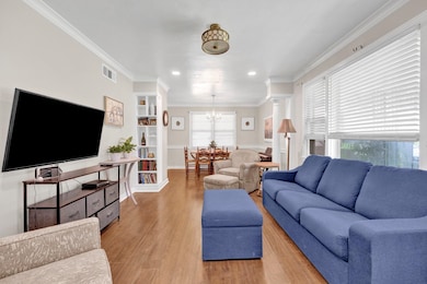 Living room with light wood-style floors, crown molding, a chandelier, recessed lighting, and baseboards