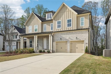 View of front of property with board and batten siding, covered porch, an attached garage, brick siding, and driveway